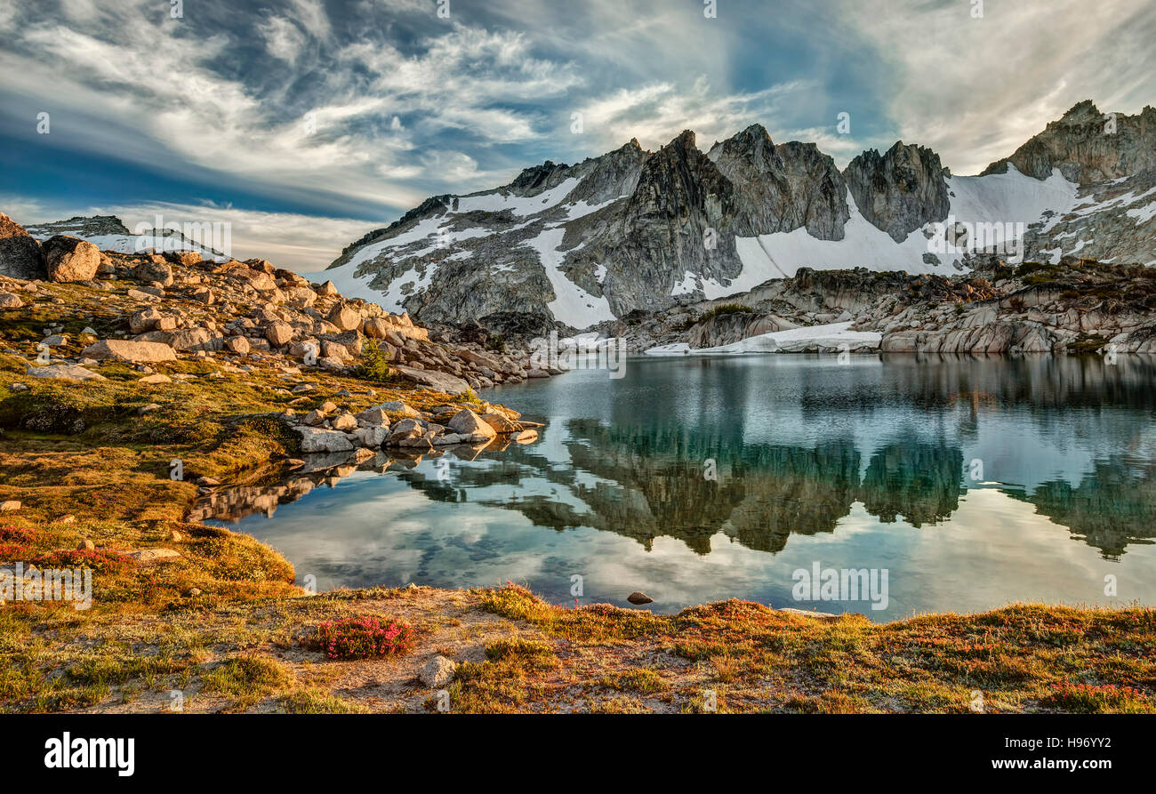 Sunset in the Upper Enchantment Basin of the Cascade Mountains in Washington state reflects in alpine lake. Stock Photo