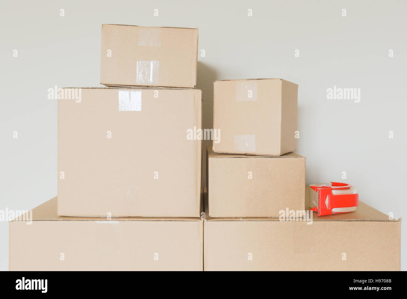 Variety of Packed Moving Boxes and Tape Gun In Empty Room Against Wall Stock Photo Alamy