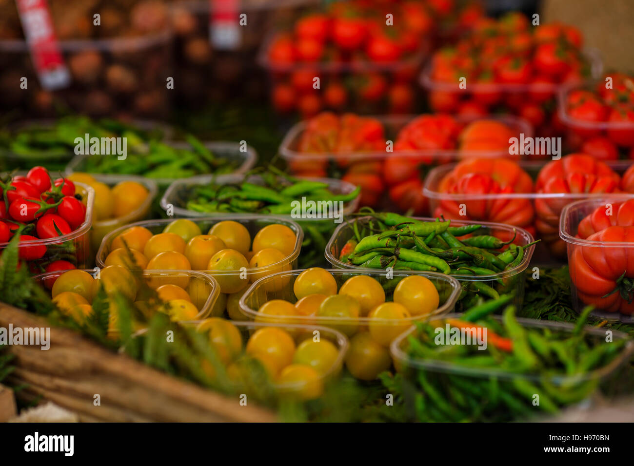 Cherry tomatoes and hot green peppers in plastic baskets at the market Stock Photo