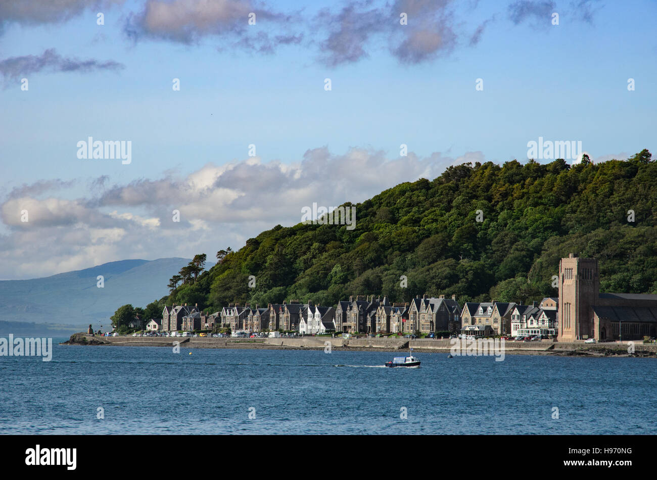 Church and houses on the foot of a hill with forest near the ferry terminal in Oban, Scotland Stock Photo