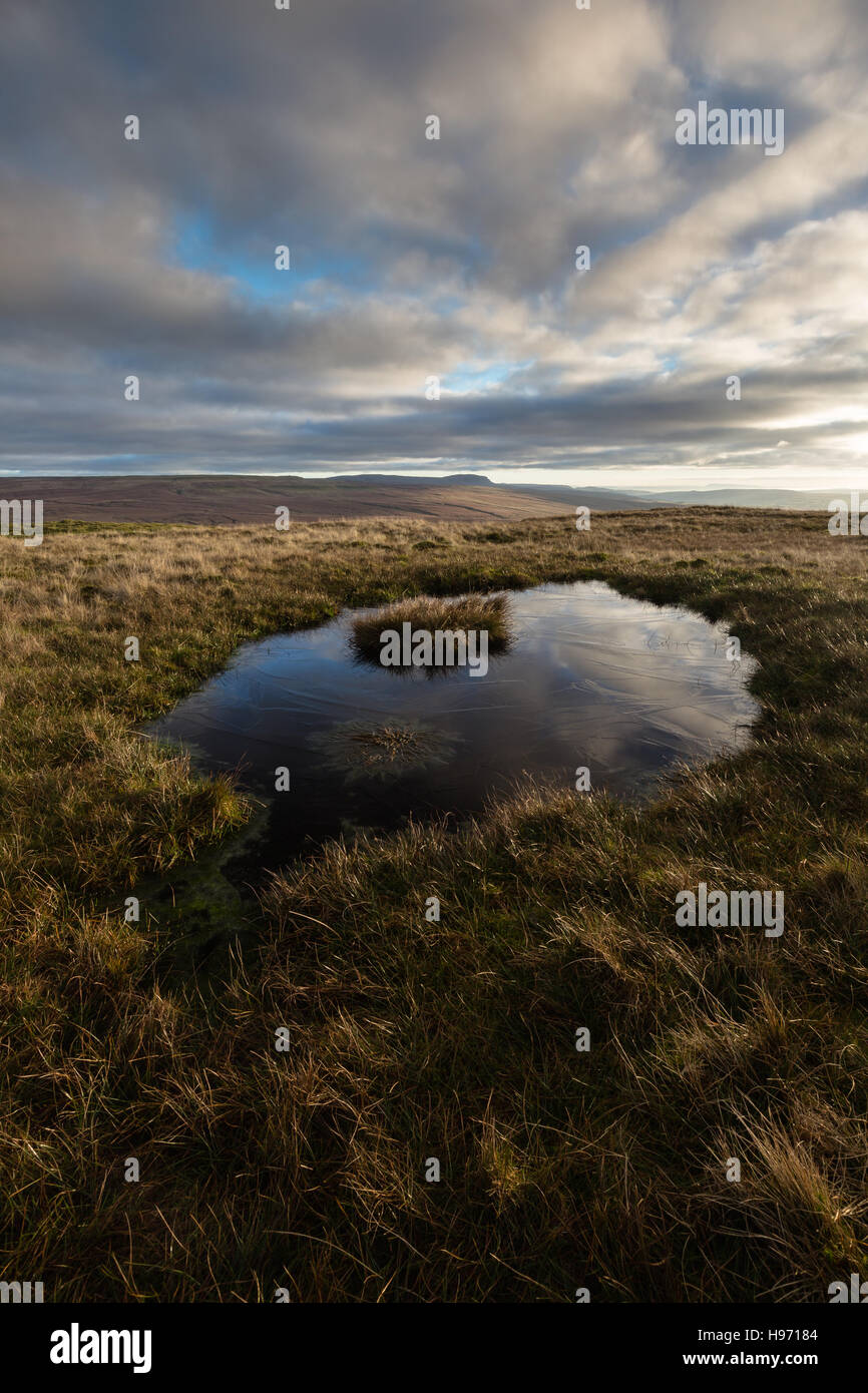 Looking over a small frozen tarn on Swineley Cowm across to Pen-y-ghent in the Yorkshire Dales, England, UK Stock Photo