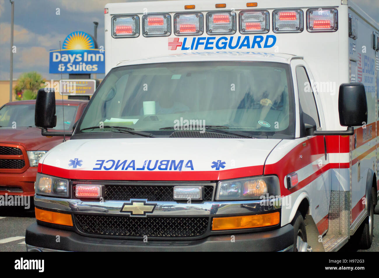 An ambulance speeding down the road with red flashing lights Stock