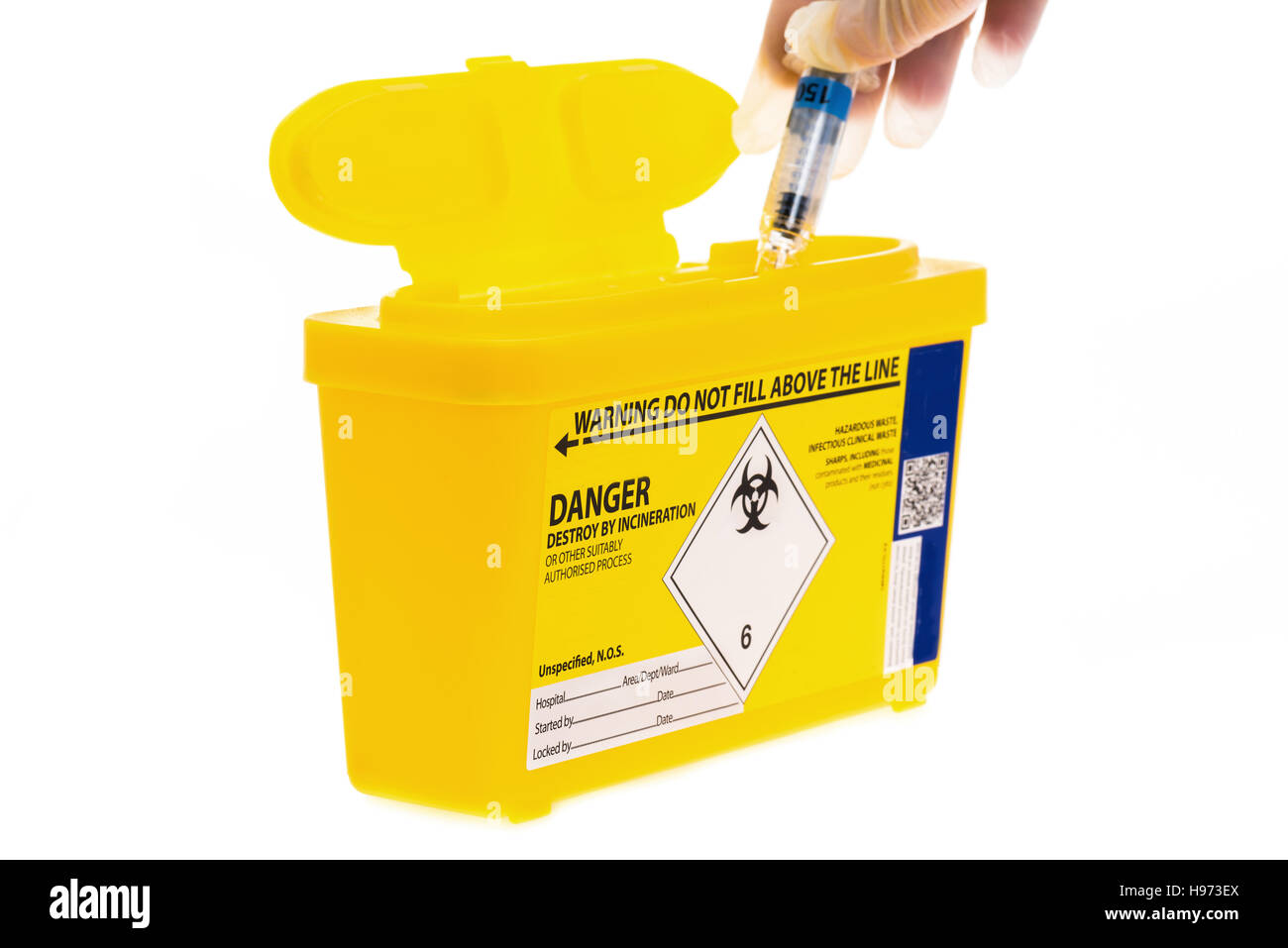 A medical sharps waste container with a used syringe being put into it