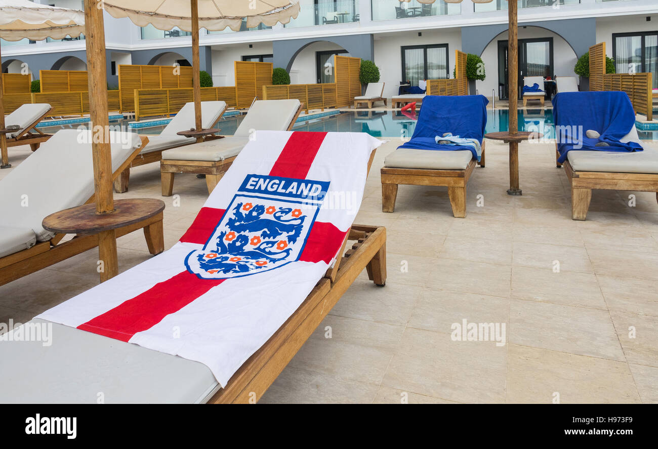 Early morning risers have reserved their sun lounger beside the swimming pool with their England flag towel. Stock Photo