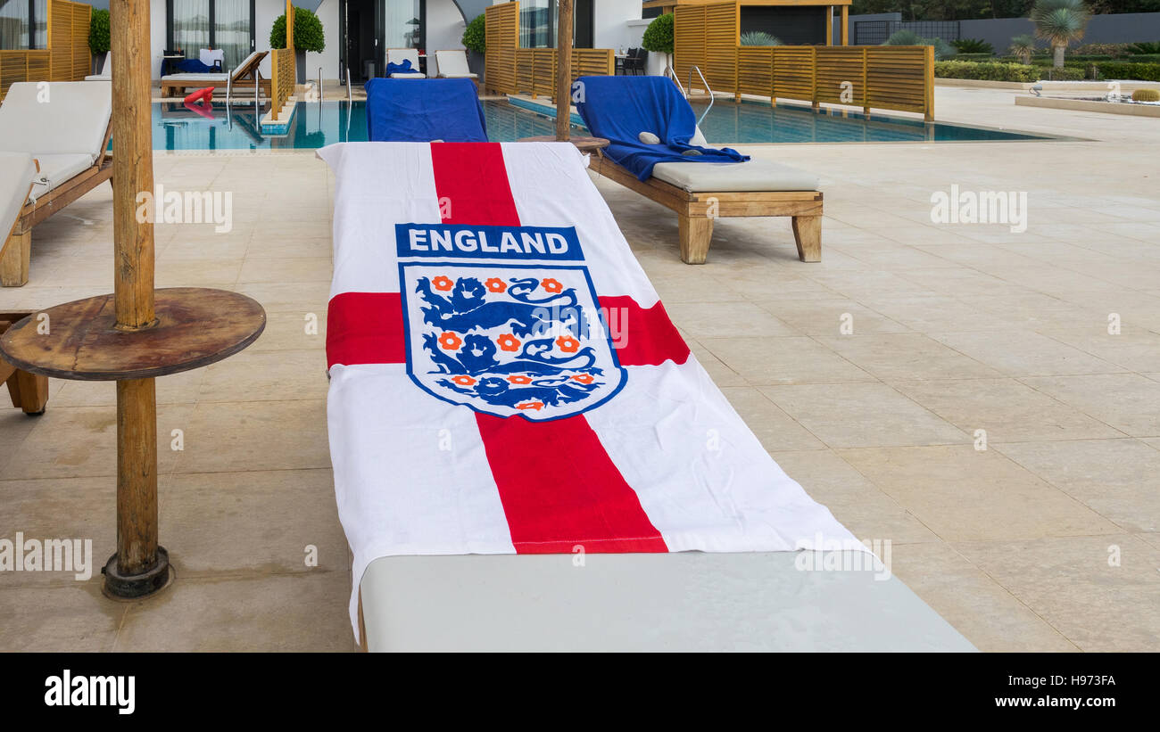 Early morning risers have reserved their sun lounger beside the swimming pool with their England flag towel. Stock Photo