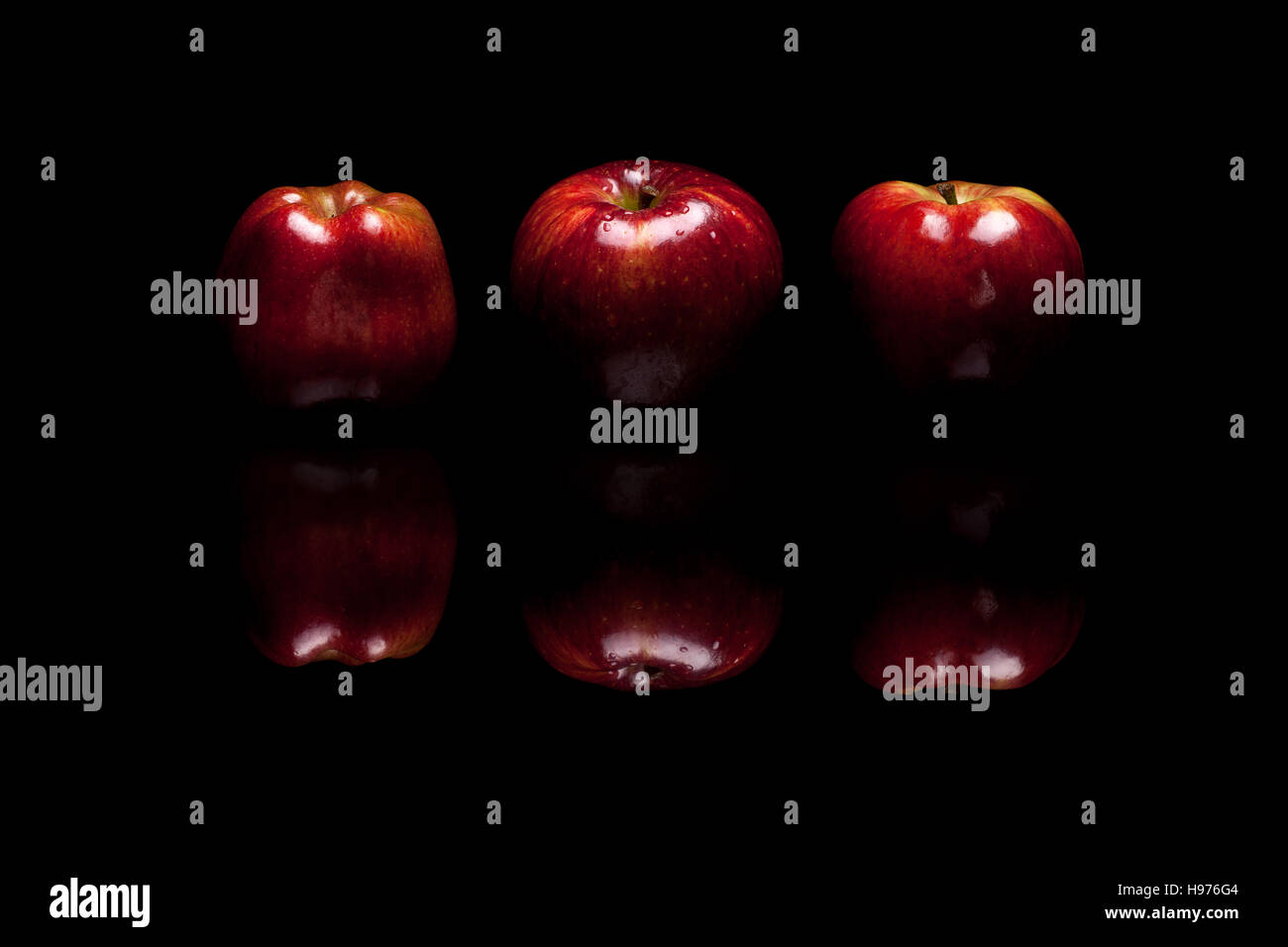 Three red apples isolated on black reflective background Stock Photo