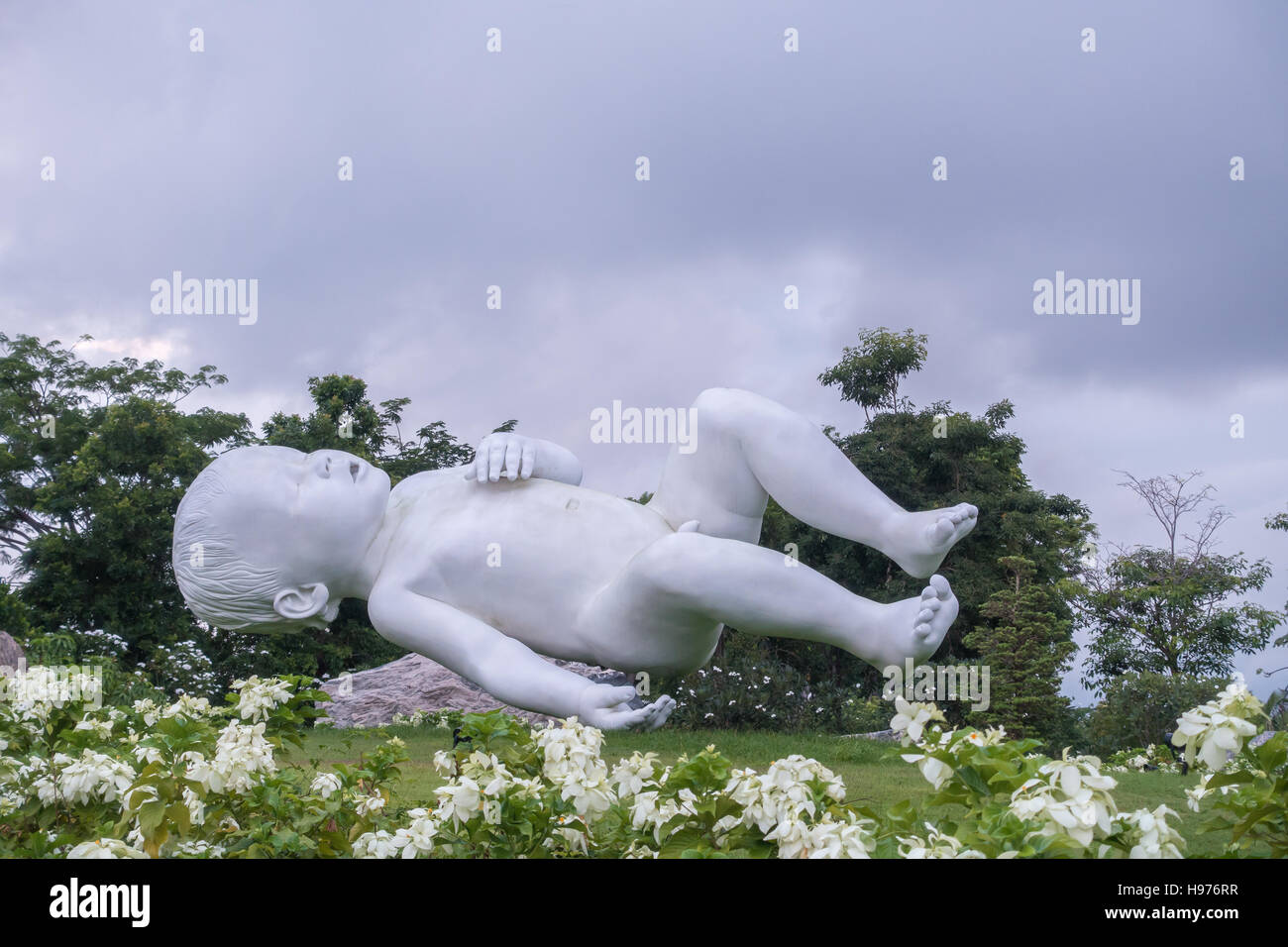 Unusual statue of a baby laying down on its back in a public park in Singapore Stock Photo