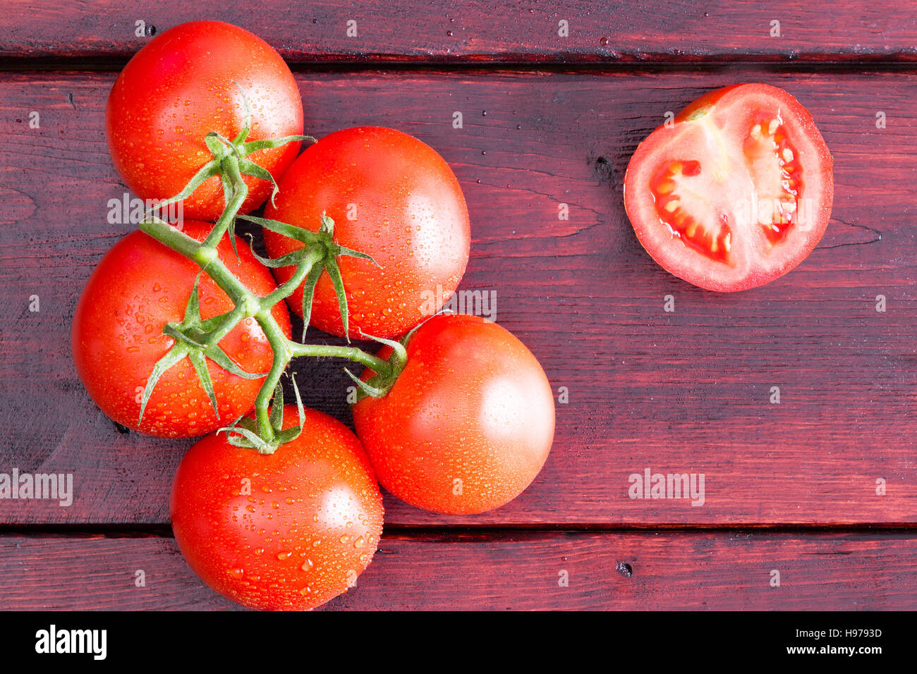 View from above on half of a tomato with moist cluster over dark stained table Stock Photo