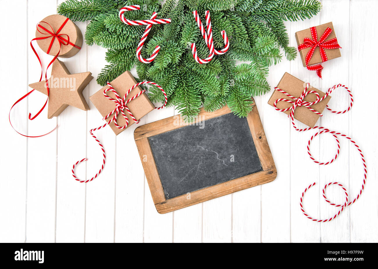Christmas decoration with chalkboard and gifts. Christmas tree branches on bright wooden background Stock Photo