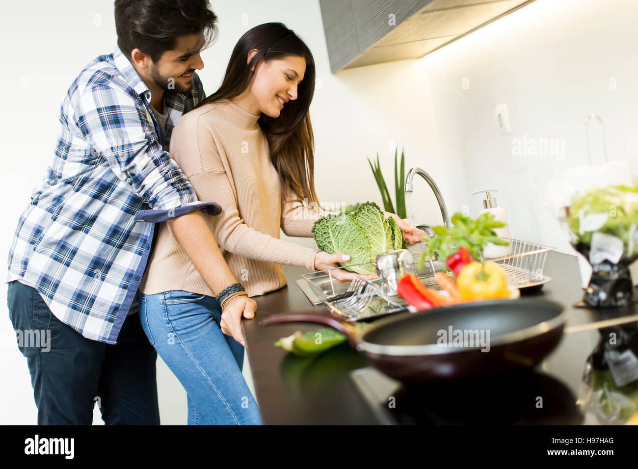 Happy young couple preparing food in the kitchen Stock Photo