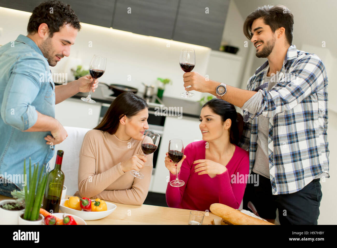 Group of happ young people sitting by the table eating and drinking red wine Stock Photo Alamy