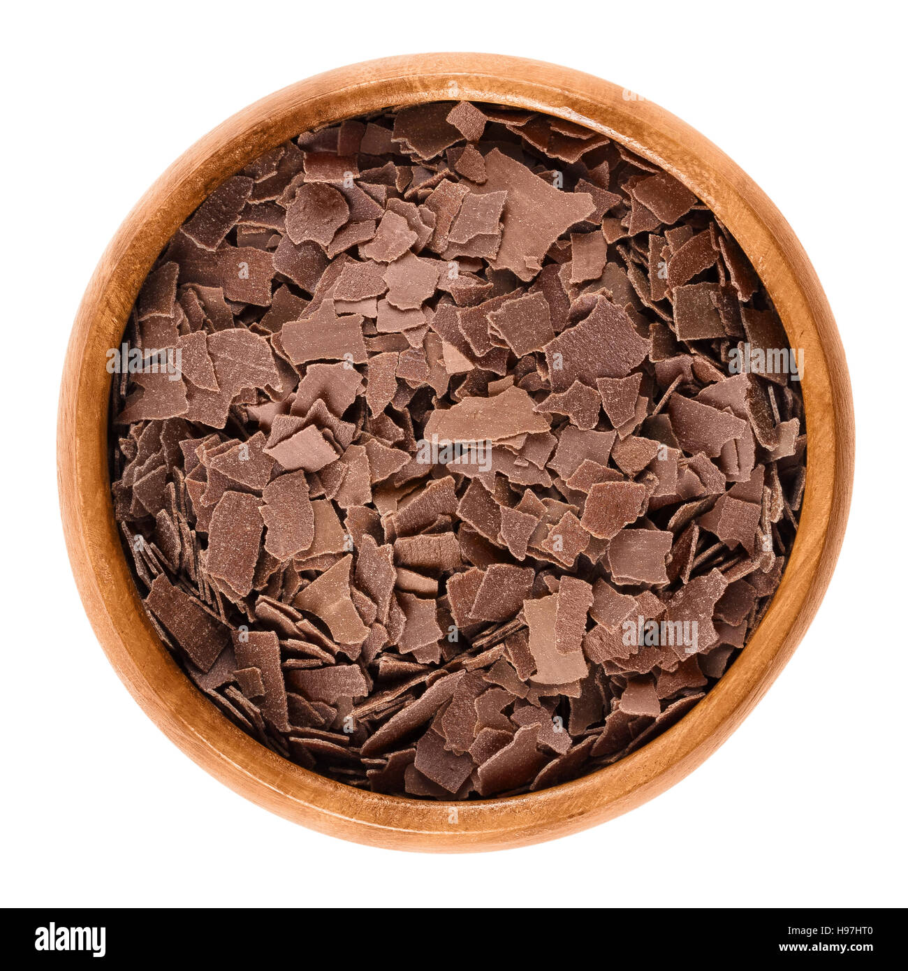 Grated milk chocolate in wooden bowl. Brown chocolate flakes to decorate cakes, pastries and biscuits. Isolated macro food photo Stock Photo