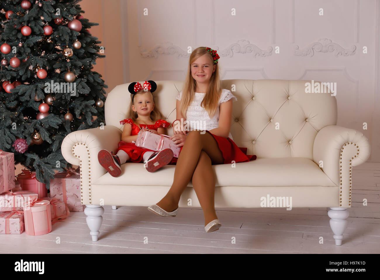 sisters girls sitting on the couch with Christmas gifts in hands Stock Photo