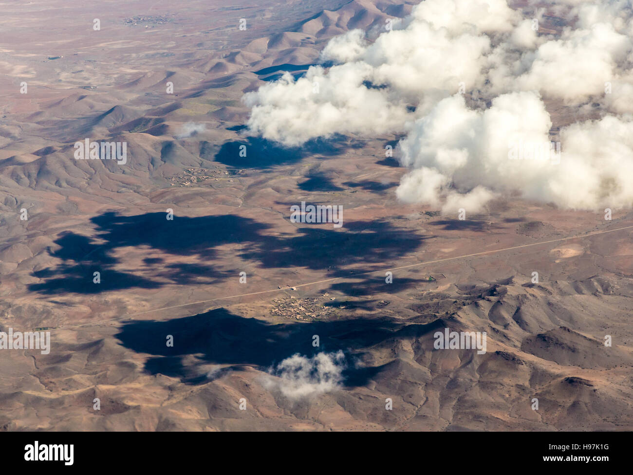 A view from plane on the mountainious countrysite and clouds. Stock Photo