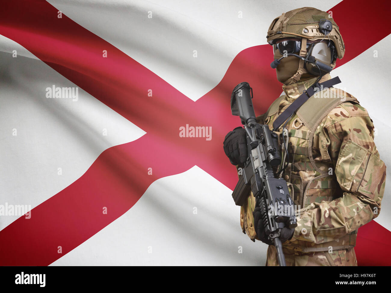 Soldier in helmet holding machine gun with USA state flag on background - Alabama Stock Photo