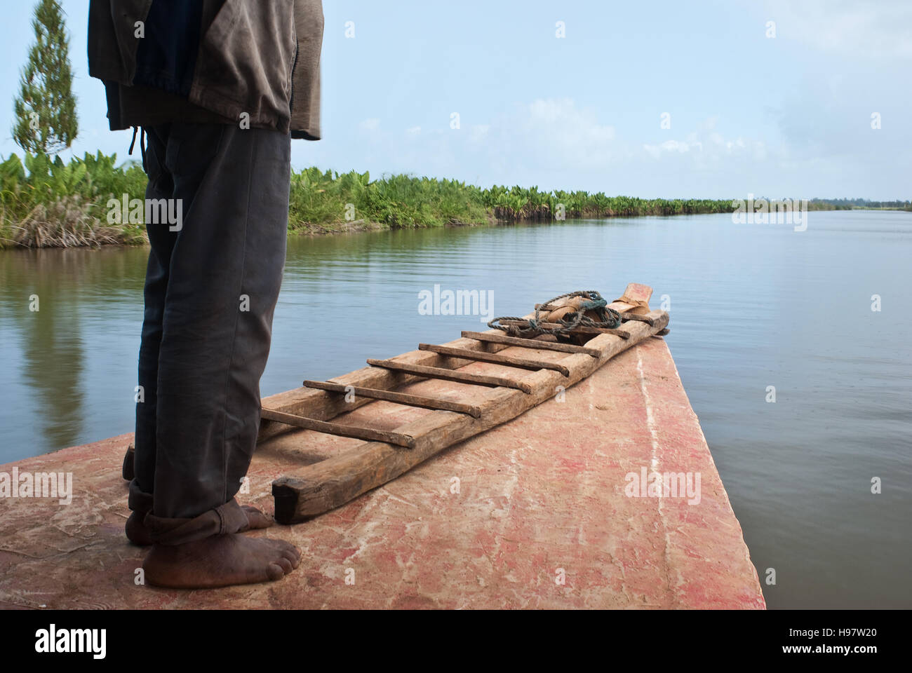 Man standing on a passenger boat that is moving along a river ( Madagascar) Stock Photo
