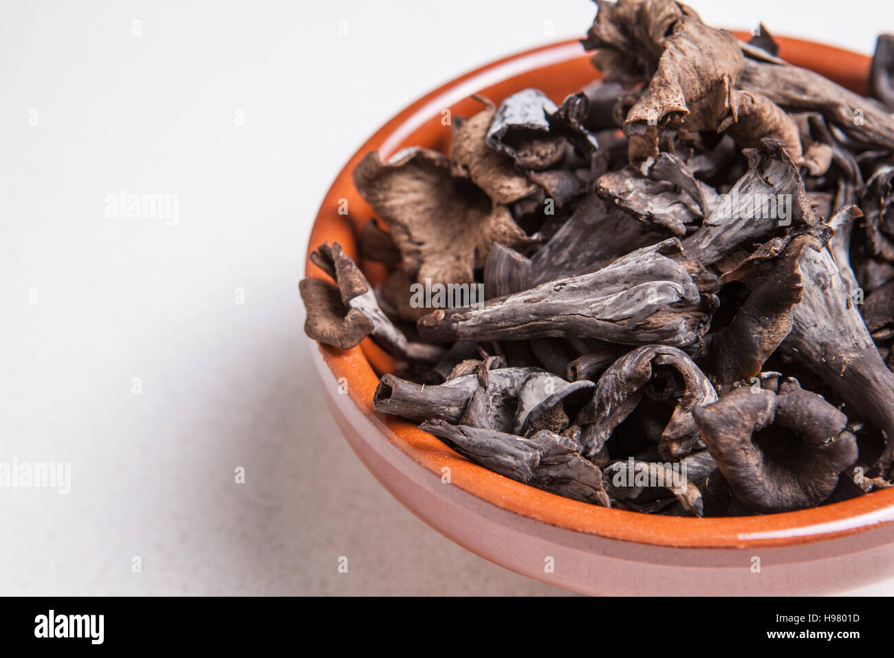 Clay bowl full of Horn of Plenty mushrooms. Isolated Stock Photo