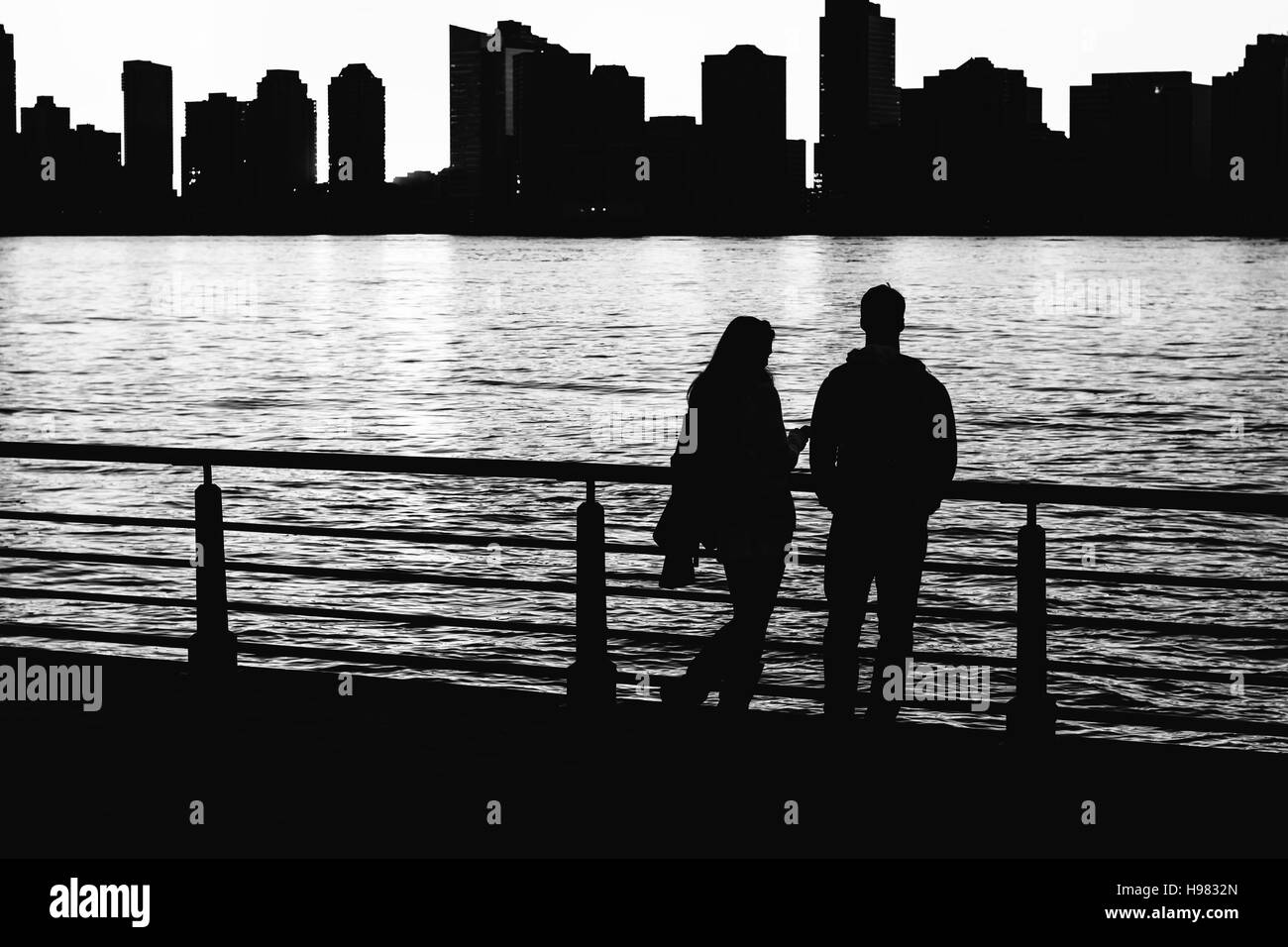 In the dark contrast of the unknown city, a mysterious couple stands in the the light Stock Photo