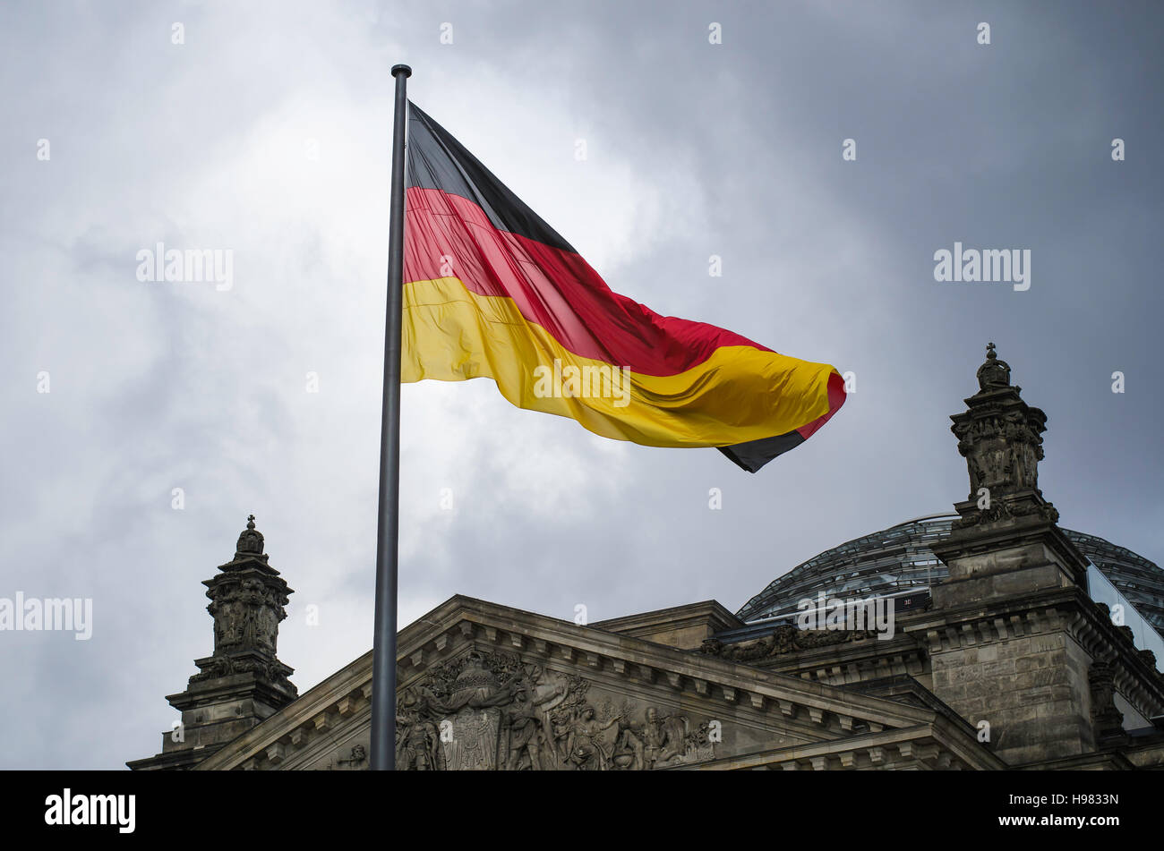 German flag flies above the Reichstag Building on an ominous day in Berlin Stock Photo