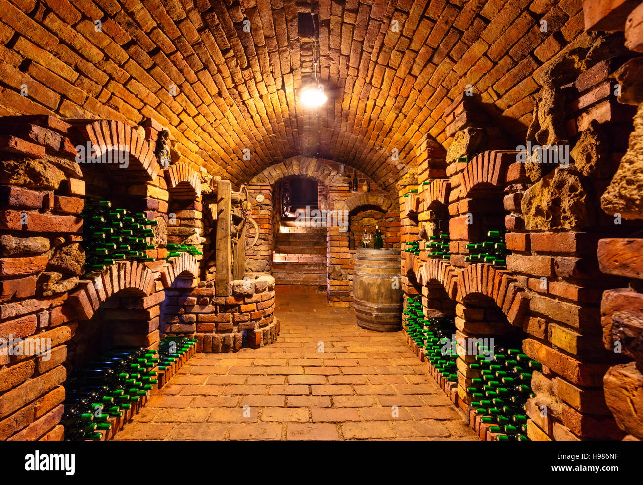 Small and old wine cellar with many full bottles and keg Stock Photo