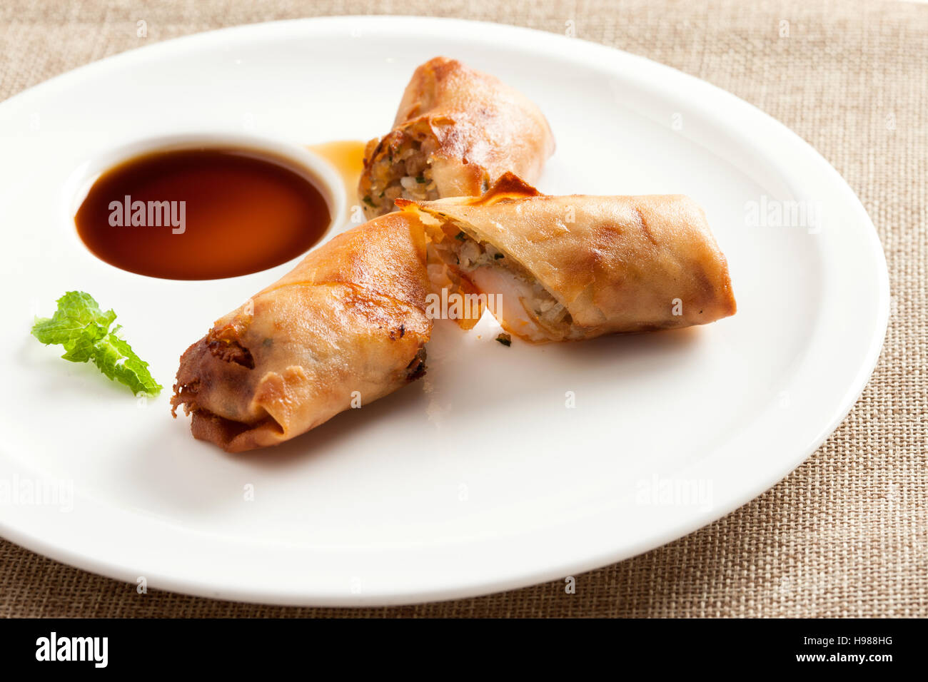 Fried spring rolls with vegetables and shrimps, served on white plate with vinegar Stock Photo