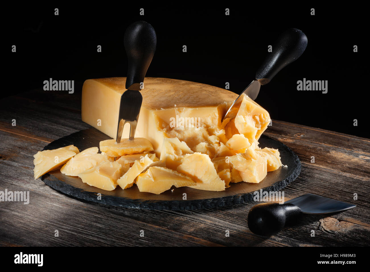 Cheese parmesan with a set of knives on  round slate board in style  rustic Stock Photo