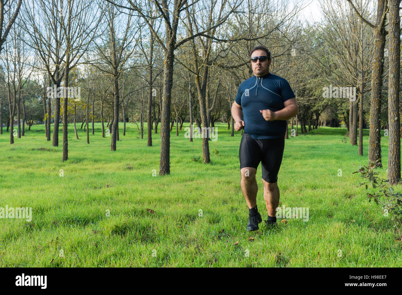 Big belly man jogging , exercising, doing cardio in the park , slightly