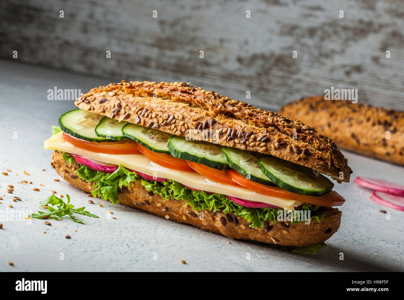 Sandwich with cheese, tomato, cucumber, radish and lettuce. Dark and moody. Stock Photo