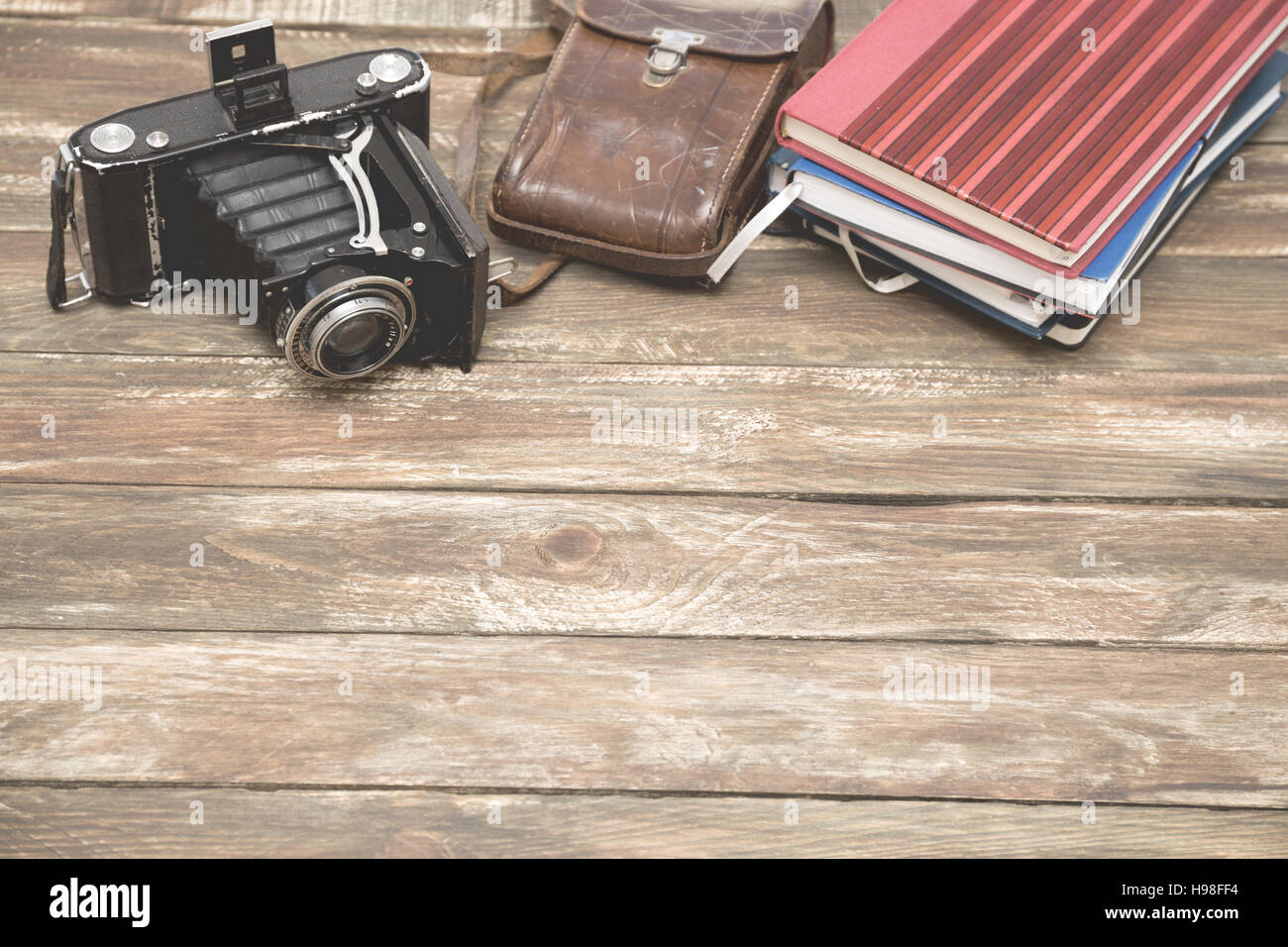 Old photocamera with leather case, notebooks on vintage wood background ...