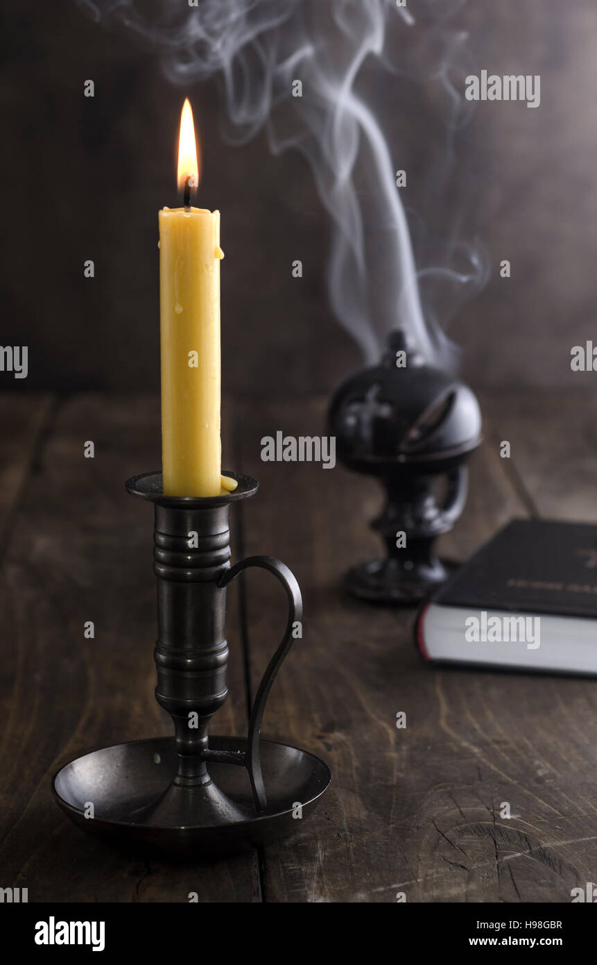 Antique candlestick and burning candle and in the background a  incense holder Stock Photo