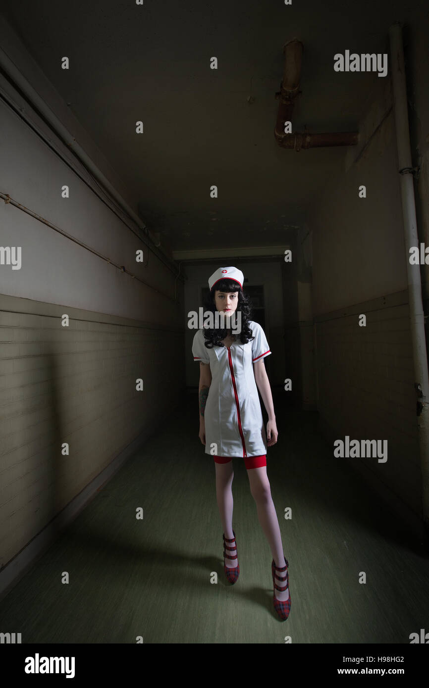 Spooky crazy nurse in derelict old and haunted asylum hospital Stock