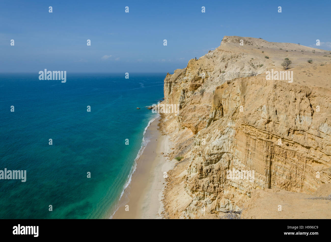 Impressive cliffs with turquoise ocean at the coast at Caotinha, Angola. The yellow sandstone drops sharply down to the sea here. Stock Photo
