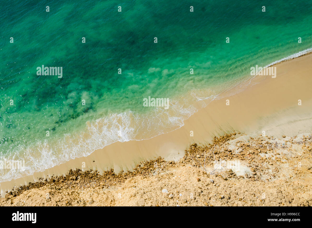 Stark contrast of beautiful turquoise blue ocean meeting yellow beach taken from the cliffs above in Caotinha, Angola. Stock Photo