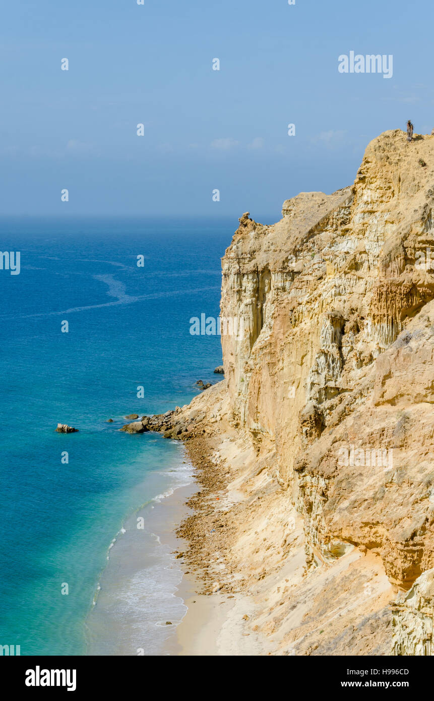 Impressive cliffs with turquoise ocean at the coast at Caotinha, Angola. The yellow sandstone drops sharply down to the sea here. Stock Photo