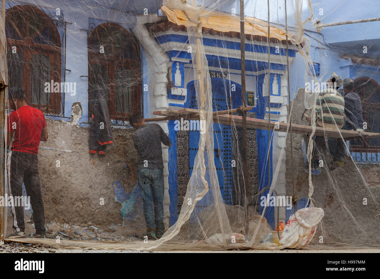 Young Men Working On The Exterior Of A House In The Medina, Chefchaouen, Morocco Stock Photo