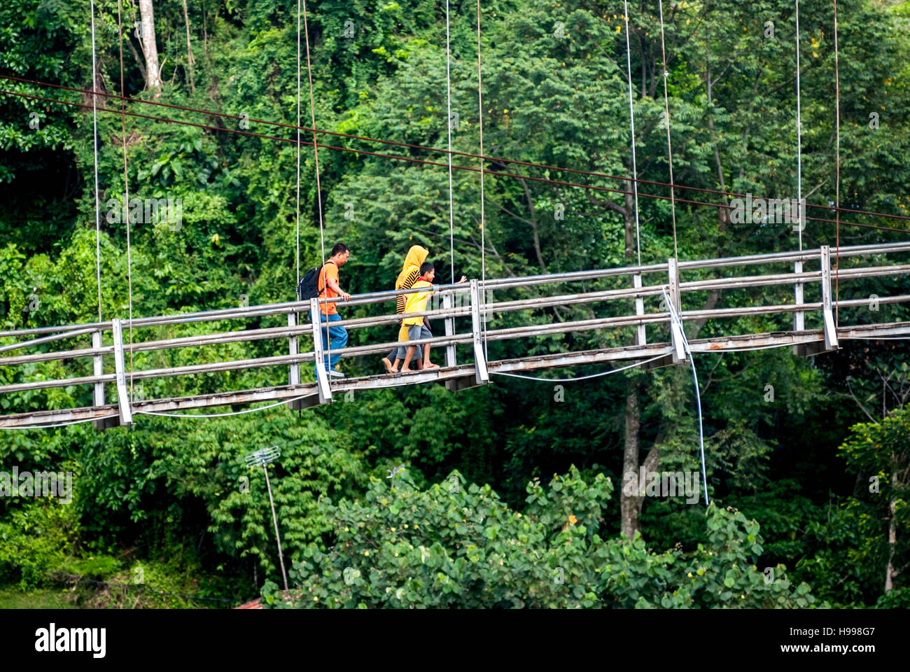 People walking on a hanging bridge, crossing over Bahorok river in Bukit Lawang, Bahorok, Langkat, North Sumatra, Indonesia. Stock Photo