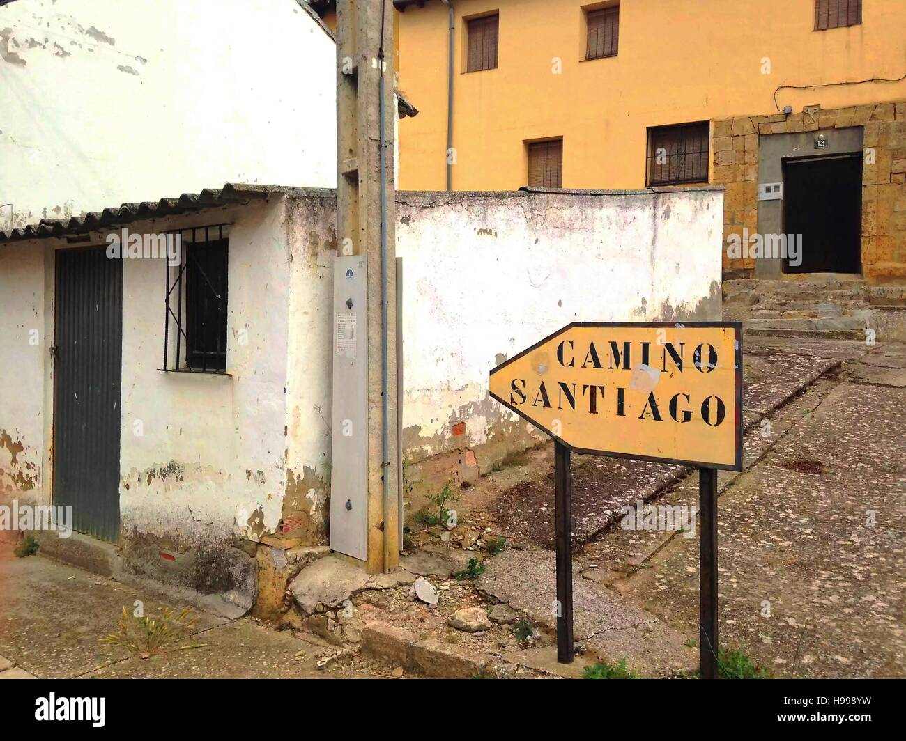 A yellow sign directs pilgrims through a rural village along the Camino Frances in northern Spain. Stock Photo