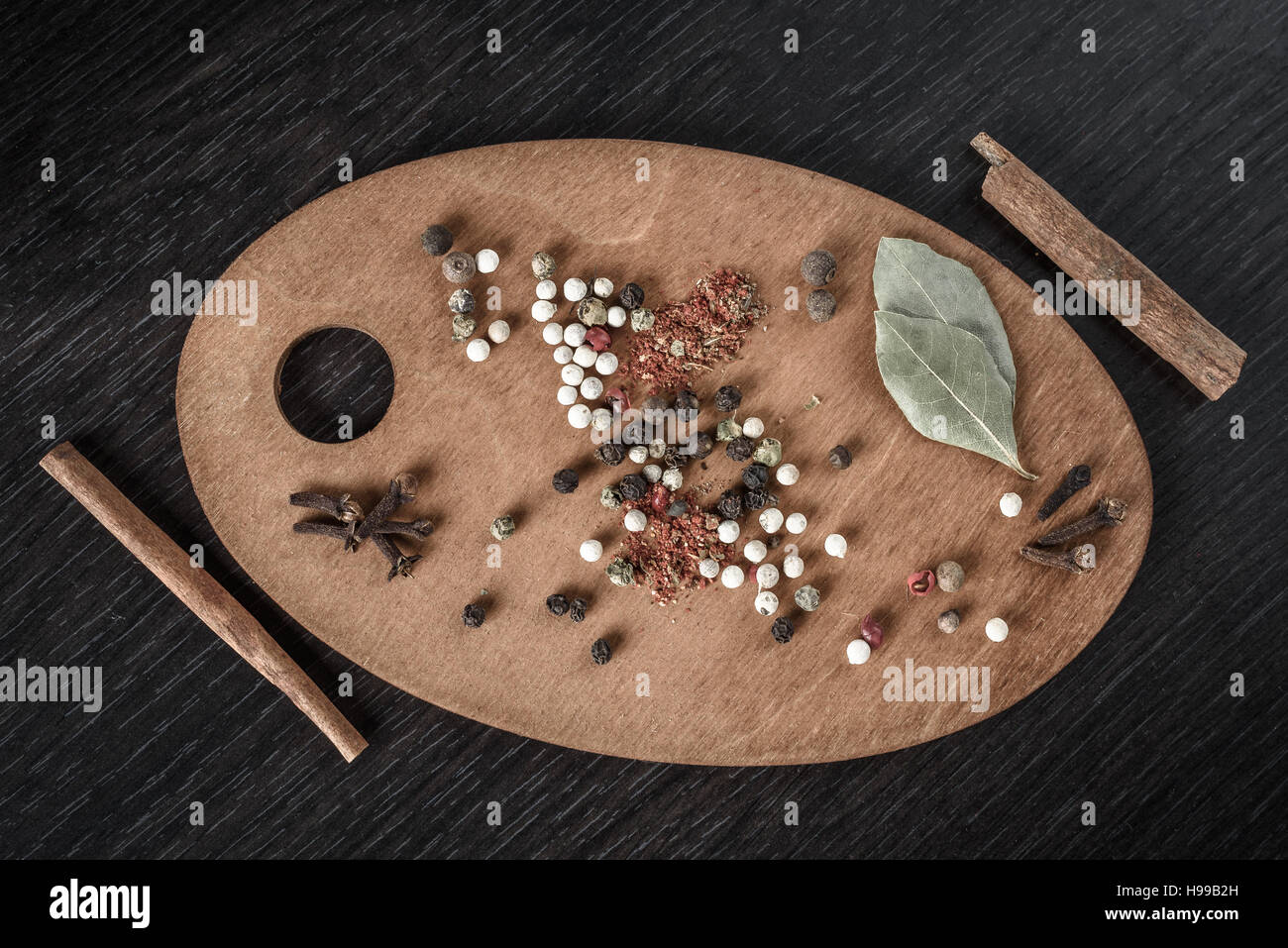 spices, black pepper, cinnamon, Bay leaf on oval wooden Board isolated on the dark backgr Stock Photo