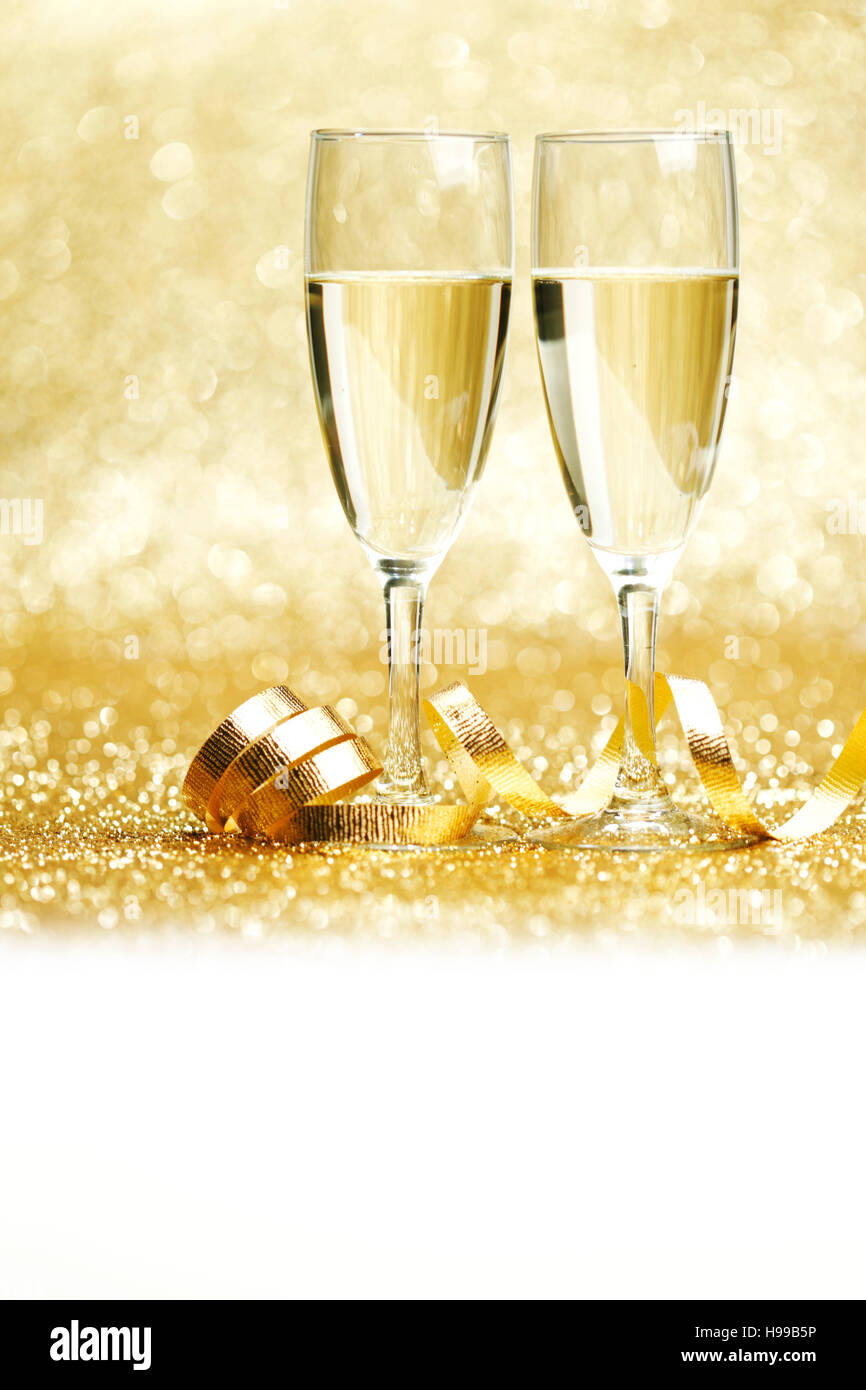 Glasses of champagne and curly decorative ribbon on golden glitters Stock Photo
