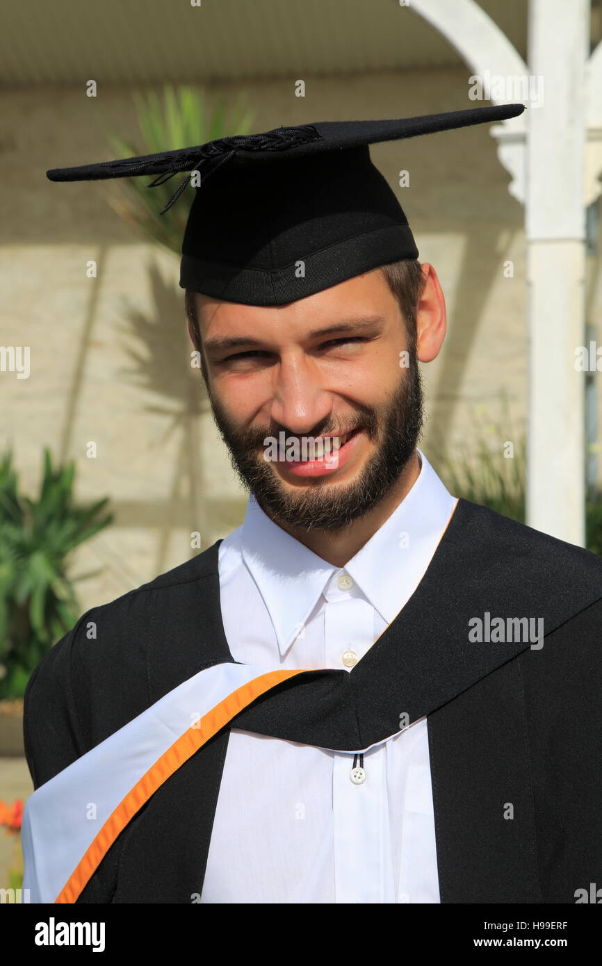 Portrait of male graduate wearing academic gown and mortarboard ...