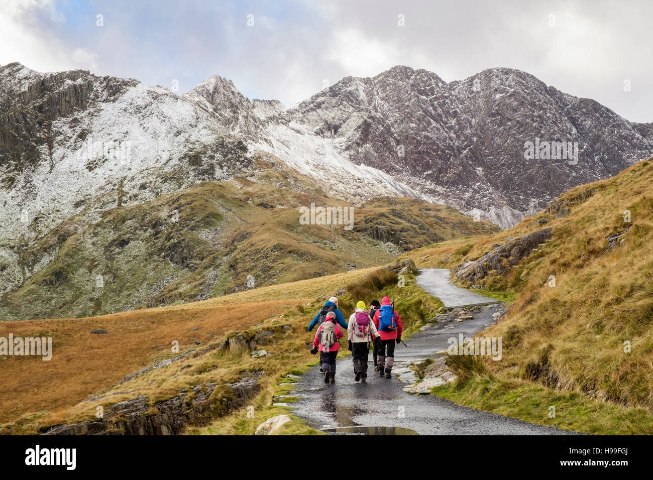 Hikers hiking on Miners' Track from Pen-y-Pass in Snowdon horseshoe with Y Lliwedd ahead and snow in winter. Snowdonia National Park (Eryri) Wales UK Stock Photo