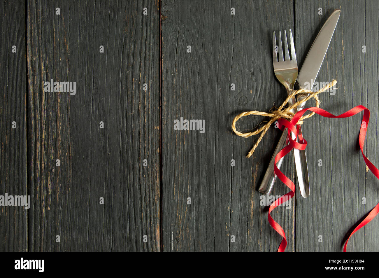 Fork and knife tied together on a wooden table with space Stock Photo