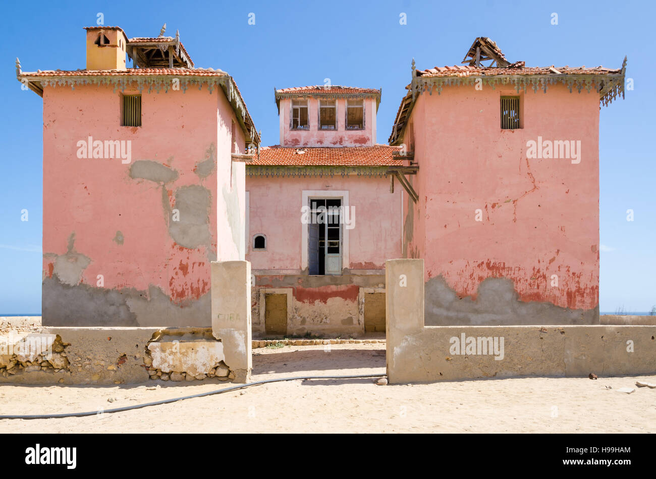 Large pink ruined mansion from Portuguese colonial times in small coastal village of Angola's Namib Desert. Stock Photo
