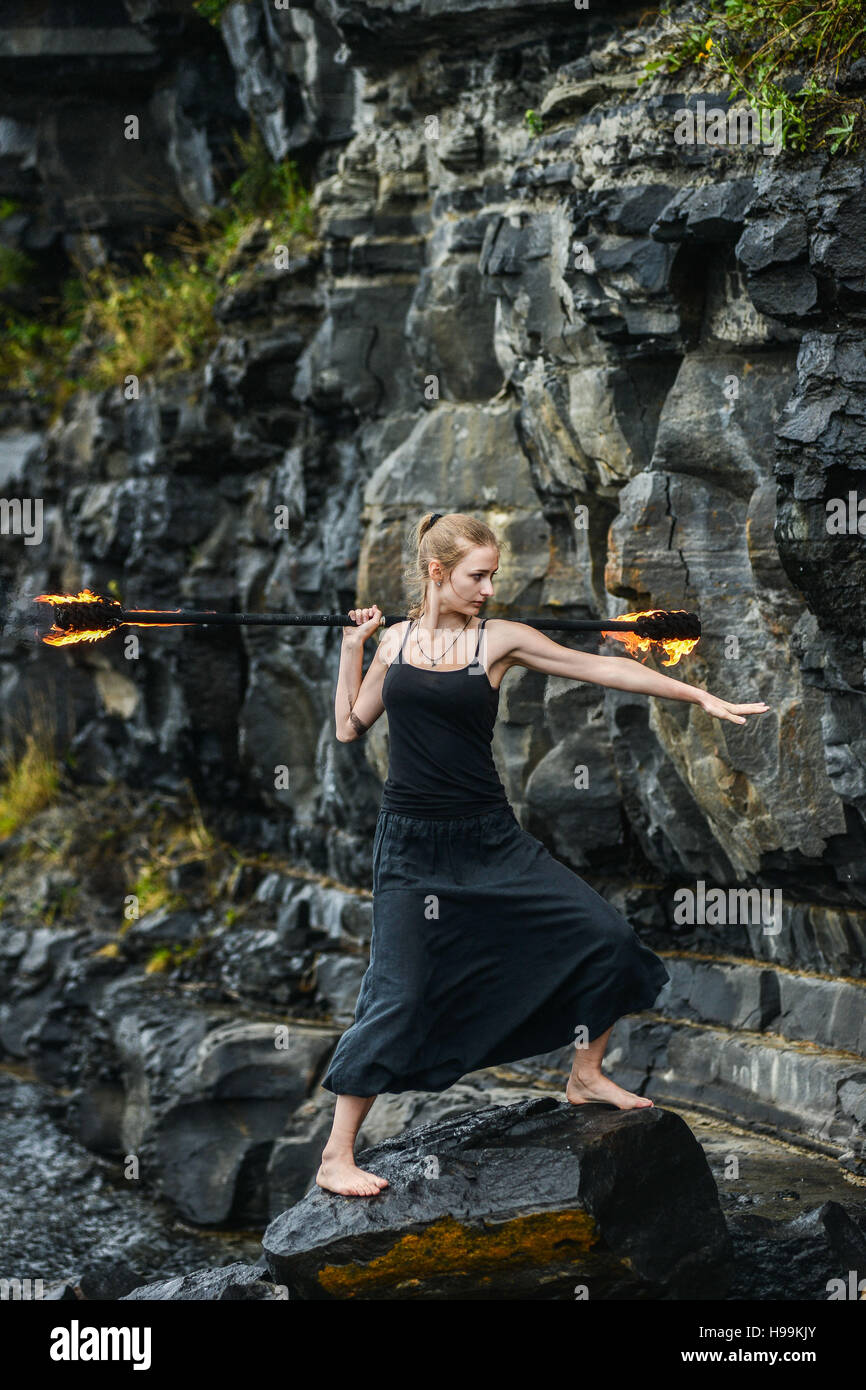 Girl in a black suit with flaming torches . Stock Photo