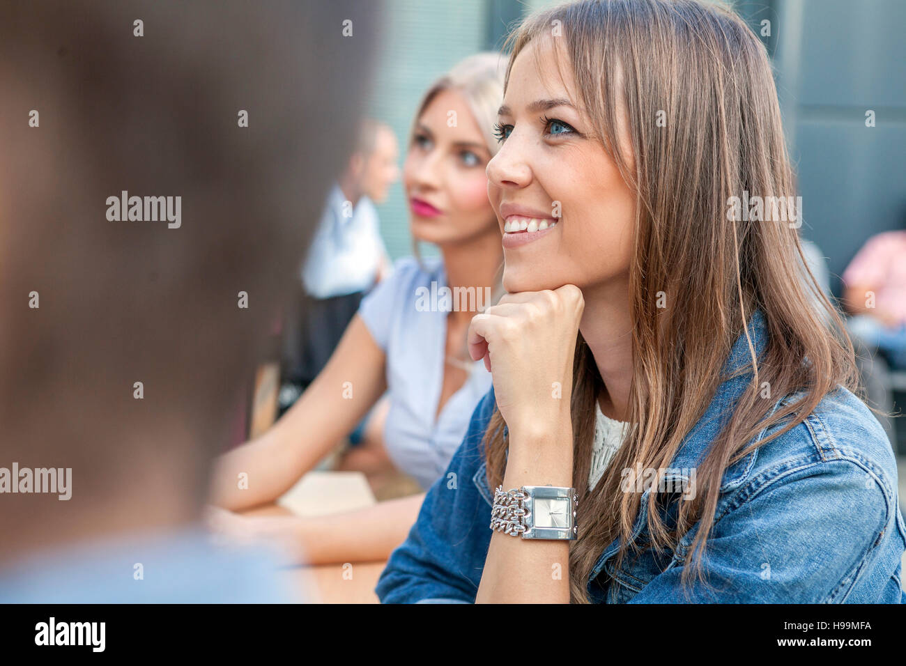 Businesswoman hand on chin listening to presentation Stock Photo