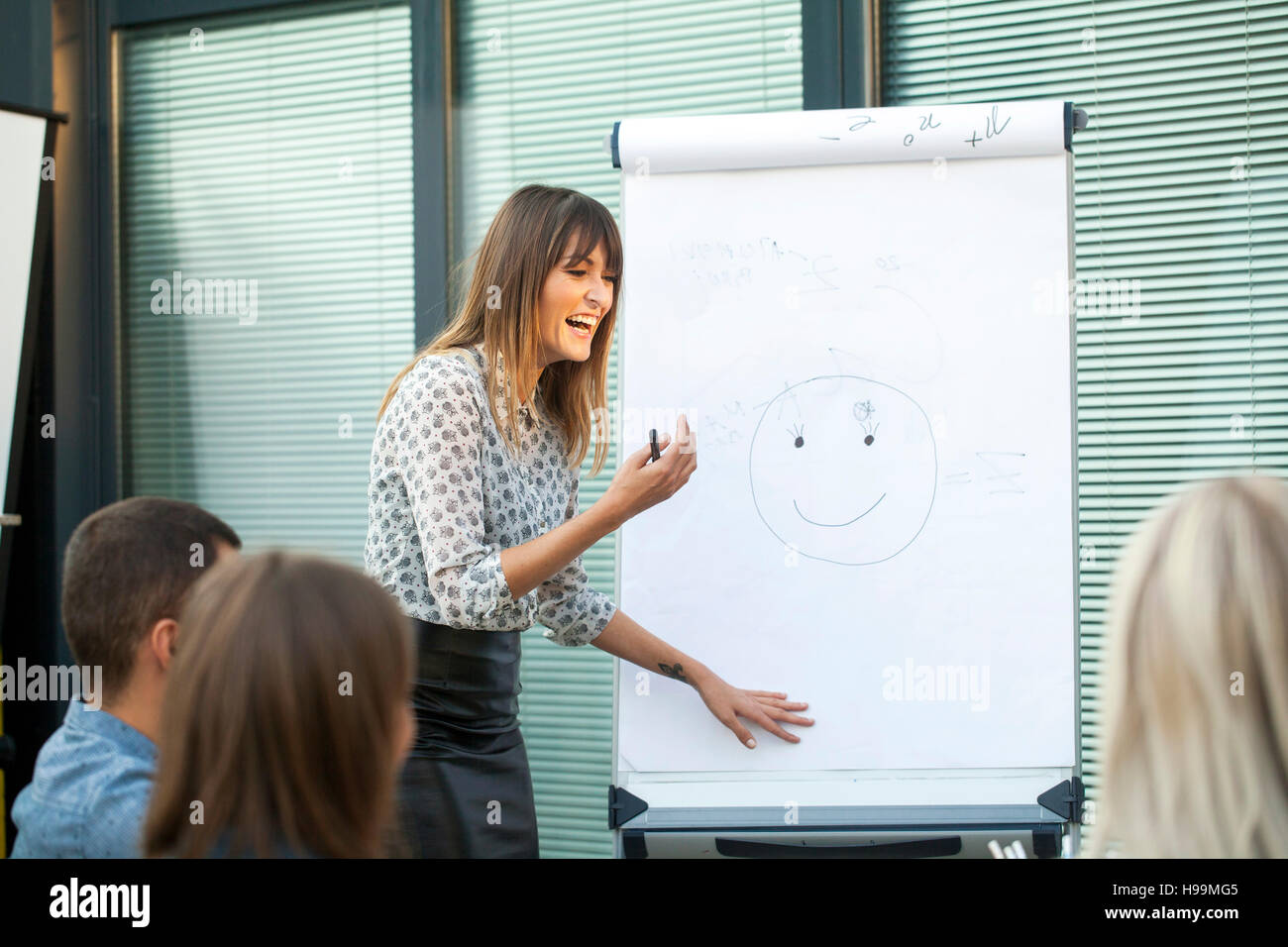 Businesswoman in workshop drawing human face on flipchart Stock Photo