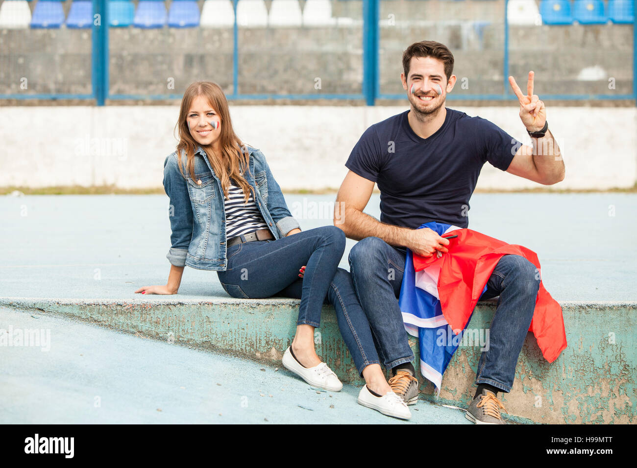 Young couple with French flag making peace sign Stock Photo