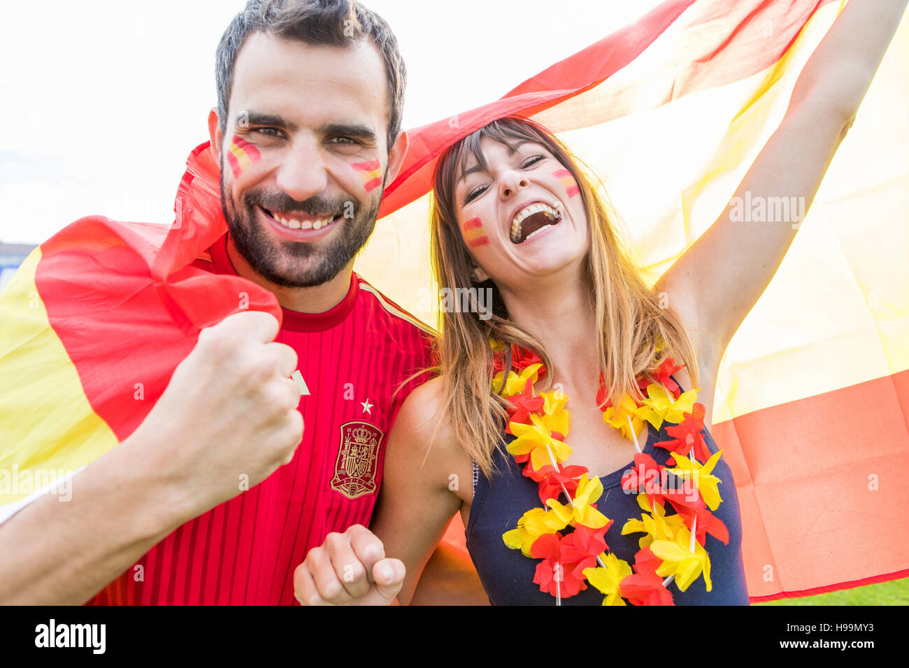 Young couple with face paint waving Spanish flag Stock Photo Alamy