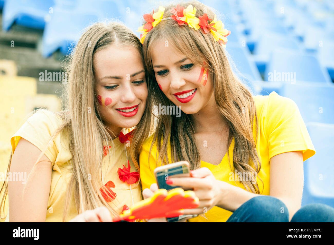Two female soccer fans text messaging in stadium Stock Photo