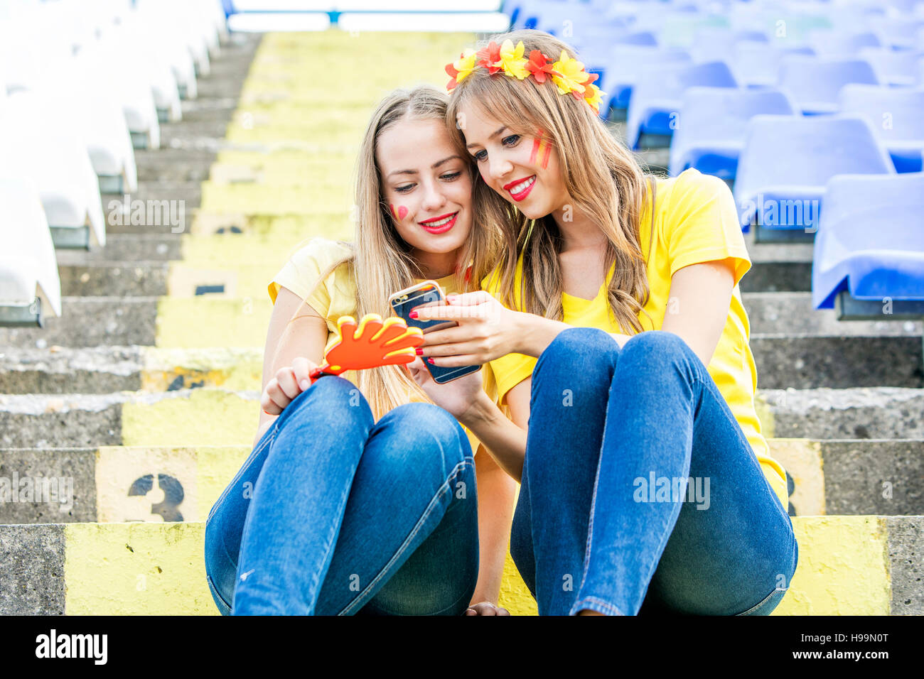 Two female soccer fans in stadium text messaging Stock Photo